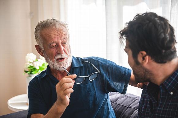 Man squinting without glasses at other man